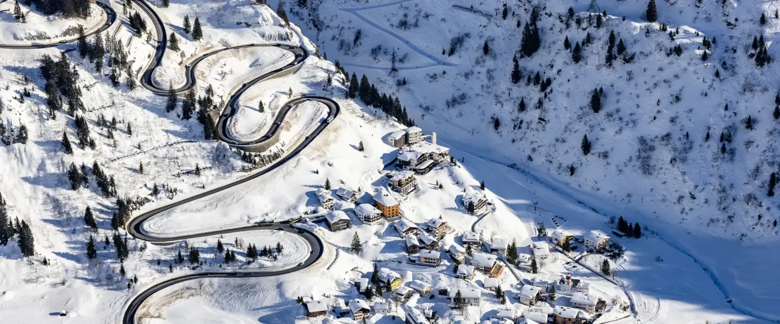 Haarspeldbochten van de Arlbergstraße boven Stuben in de sneeuw, van boven gezien