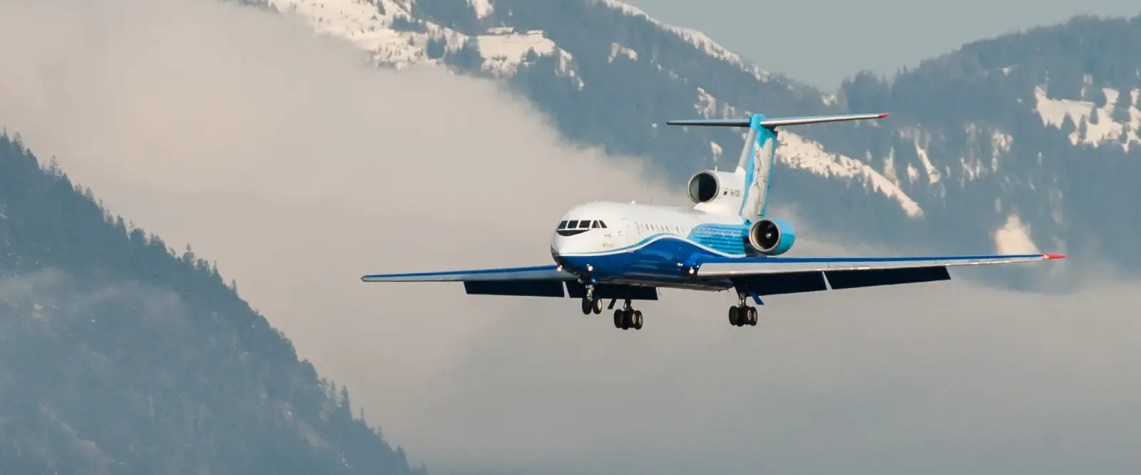 Passagiersvliegtuig in de landing boven besneeuwde bergen bij Innsbruck